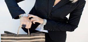 Poslovna žena u crnom sakou pokazuje prstom na ručni sat
